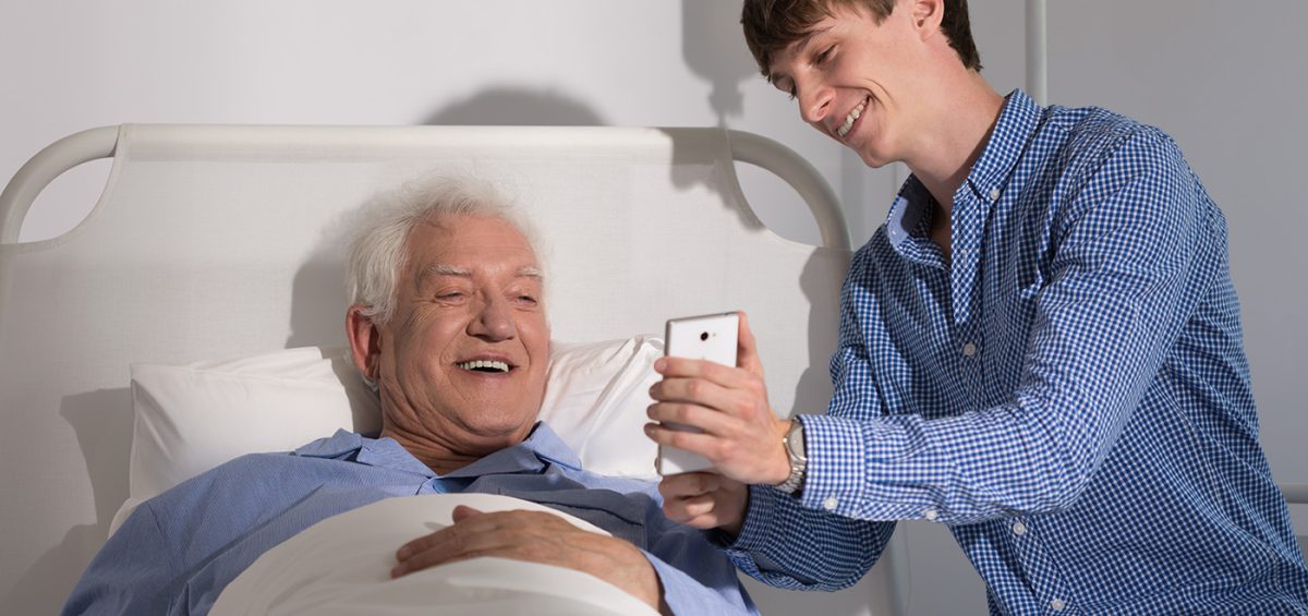 Young Man Helping Hospice Patient Record A Message